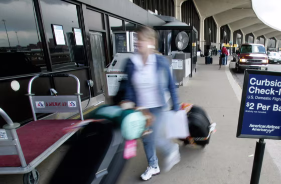 Image: A woman wheels her bags into the American Airlines terminal at Newark International Airport